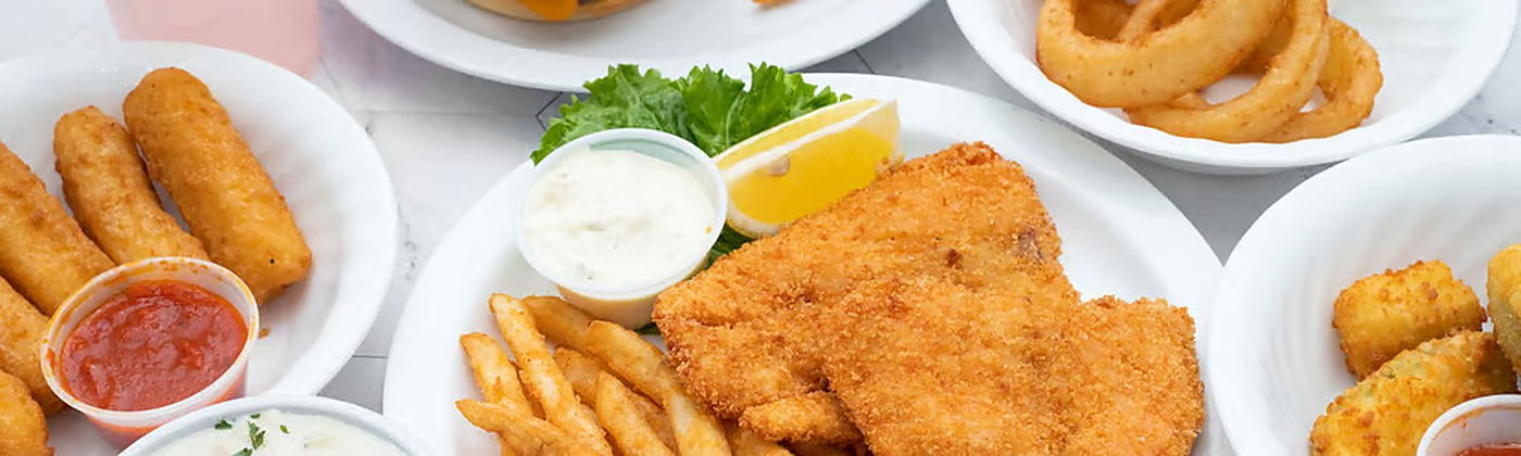 Assorted fried seafood plates with fries, onion rings and dipping sauces